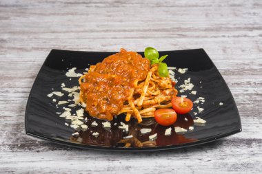 Hafif ahşap üzerine siyah bir tabak makarna. Tagliatelle mantarlı domates ve bolognese