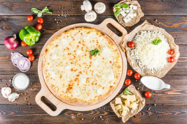 Koyu ahşap arka plan üzerinde yuvarlak kesme tahtası üzerinde büyük peynirli pizza. Pizza malzemeleri