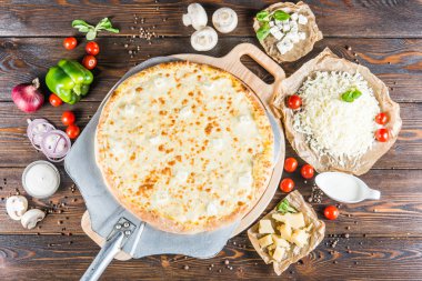 Koyu ahşap arka plan üzerinde bir kürek üzerinde büyük cheesepizza. Pizza malzemeleri