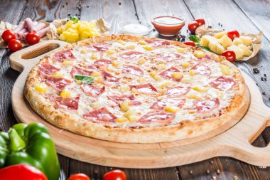 Jambon ve ananas yuvarlak kesme tahtası koyu ahşap arka plan üzerinde büyük pizza. Gıda katkı maddeleri. Makro