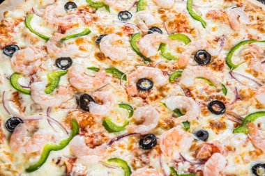 Deniz ürünleri, karides ve yuvarlak kesme tahtası koyu ahşap arka plan üzerinde siyah zeytin büyük pizza. Gıda katkı maddeleri. Makro