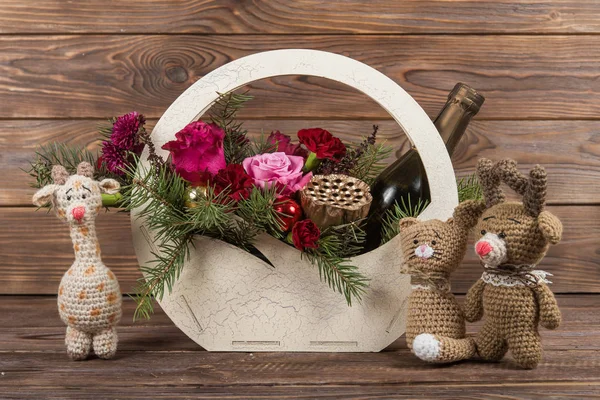Christmas basket of flowers with champagne. New Year\'s gifts. Crochet toys
