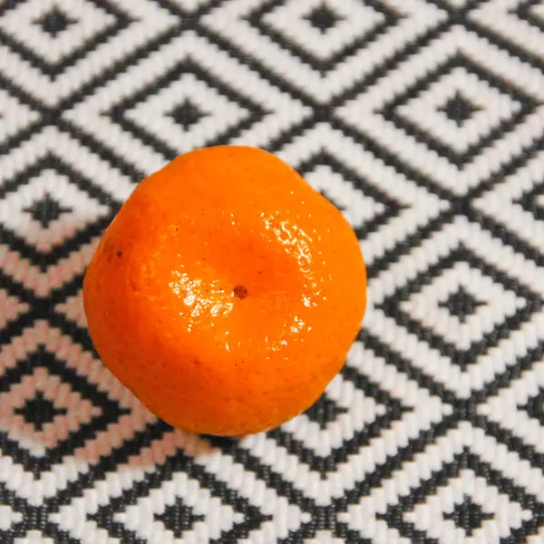 Ткань, текстура, ромбы. Один мандарин на фоне рома — стоковое фото