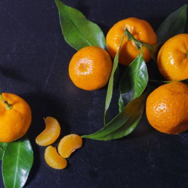 Siyah bir arka planda yaprakları ile mandalinler. Koyu bir ba üzerinde turuncu