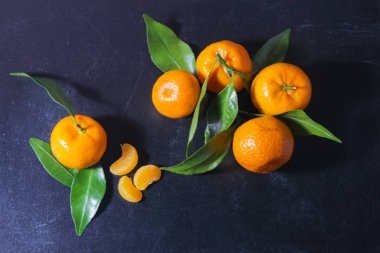 Siyah bir arka planda yaprakları ile mandalinler. Koyu bir ba üzerinde turuncu