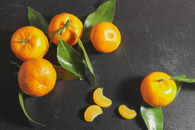 Siyah bir arka planda yaprakları ile mandalinler. Koyu bir ba üzerinde turuncu