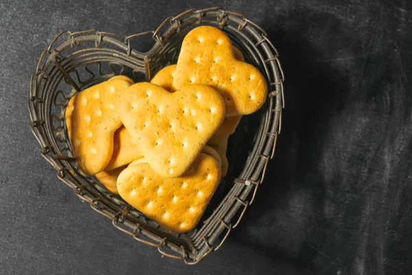 A heart cookie, in a vase in the shape of a heart on a dark back