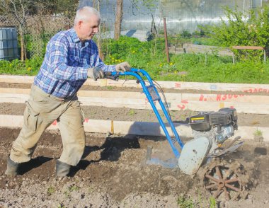 Çiftçi motor bloğu ile yere pulluklar. Grou çiftçilik