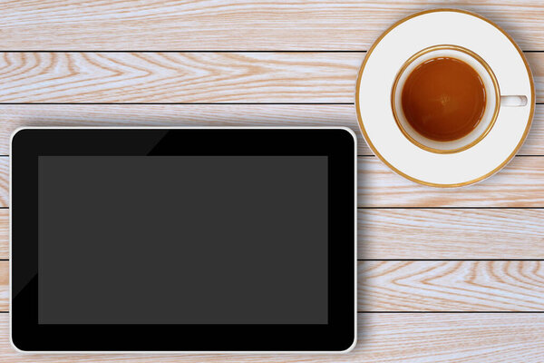 tablet computer and coffee cup on wooden background