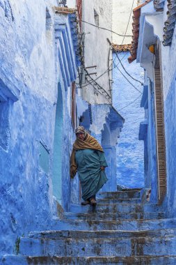 Tipik Fas giyimli bir kadın, Chefchaouen mavi Medine bir sokakta yürürken