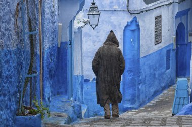 Tipik Fas giyimli bir adam, Chefchaouen mavi Medine bir sokakta yürürken
