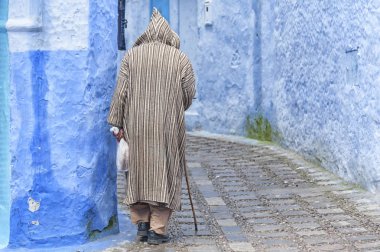 Chefchaouen, Fas - 19 Şubat 2017: Chefchaouen'in mavi medinesinde yürüyen kimliği belirsiz adam