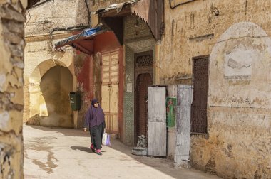 Meknes, Fas - 18 Şubat 2017: Fas'ın Meknes kentinde ki sokakta yürüyen kimliği belirsiz kadın. Meknes Fas'ın dört İmparatorluk şehrinden biridir.