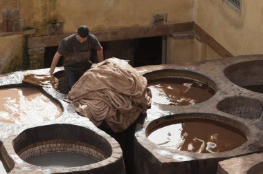 Fez, Fas - 20 Şubat 2017: Fez Medine'deki ünlü Chouara Tabakhane'deki boya deliklerinde çalışan kimliği belirsiz adam.