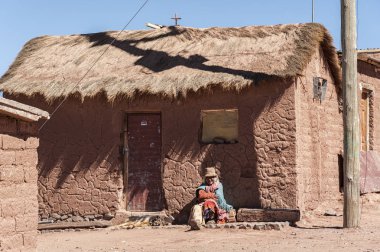 Kimliği belirsiz yaşlı kadın Bolivian Altiplano, Bolivya-Güney Amerika 'da Cerrillos köyünde bir Adobe House önünde oturuyor