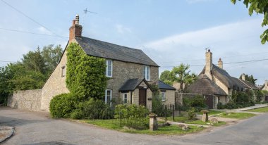 Narrow lane with romantic thatched houses and stone cottages in the lovely Minster Lovell village, Cotswolds, Oxfordshire, England  clipart