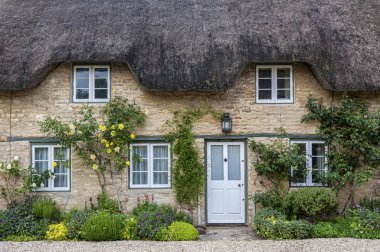 Narrow lane with romantic thatched houses and stone cottages in the lovely Minster Lovell village, Cotswolds, Oxfordshire, England  clipart