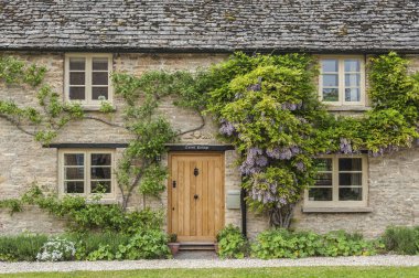 Narrow lane with romantic thatched houses and stone cottages in the lovely Minster Lovell village, Cotswolds, Oxfordshire, England  clipart