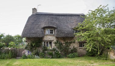 Narrow lane with romantic thatched houses and stone cottages in the lovely Minster Lovell village, Cotswolds, Oxfordshire, England  clipart