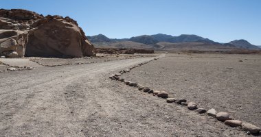 Şili'de Atacama Çölü'ndeki Yerbas Buenas Kayalıkları üzerinde Antik Petroglifler yakınında asfaltsız yol