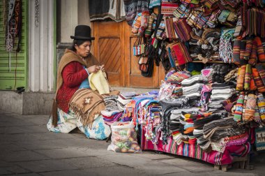 LA PAZ, BOLIVIA - AUGUST 19, 2017 : Unidentified street woman vendor wearing traditional clothing in the local Rodriguez market, selling souvenirs, in La Paz - Bolivia clipart