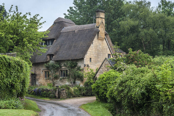 STANTON, ENGLAND - MAY, 26 2018: Thatched cottage in the village of Stanton, Cotswolds district of Gloucestershire.  It's built almost completely of Cotswold stone, a honey-coloured Jurassic limestone