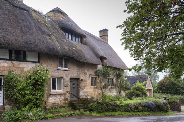 STANTON, ENGLAND - MAY, 26 2018: Thatched cottage in the village of Stanton, Cotswolds district of Gloucestershire.  It's built almost completely of Cotswold stone, a honey-coloured Jurassic limestone