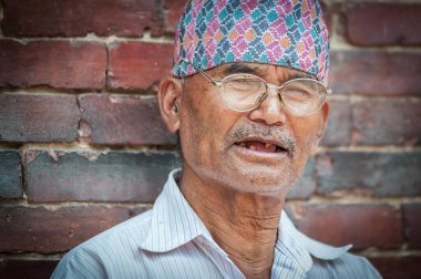 PATAN, LALITPUR, NEPAL - 15 Ağustos 2018: Tanımlanamayan Newari yaşlısı Patan Durbar Meydanı 'ndaki Mul Chowk Kraliyet Sarayı önünde oturuyor