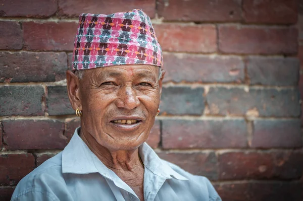 PATAN, LALITPUR, NEPAL - 15 Ağustos 2018: Tanımlanamayan Newari yaşlısı Patan Durbar Meydanı 'ndaki Mul Chowk Kraliyet Sarayı önünde oturuyor