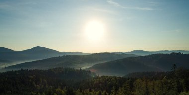  Yaz mevsiminde güneş ve çam ağaçlarıyla birlikte güneş doğar. Kayalarla manzara, bulutlarla güneşli gökyüzü