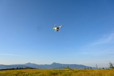 Siluet Drone dağda uçuyor, bulutlarla gün doğumunda gökyüzünde, hava fotoğrafçılığıyla. Dağlar, güneş ve çam ağaçlarıyla kaplı. Gün doğumu