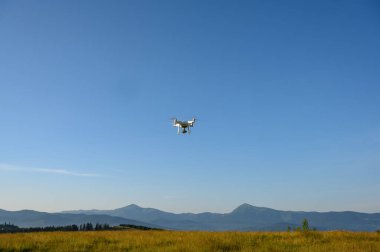 Siluet Drone dağda uçuyor, bulutlarla gün doğumunda gökyüzünde, hava fotoğrafçılığıyla. Dağlar, güneş ve çam ağaçlarıyla kaplı. Gün doğumu