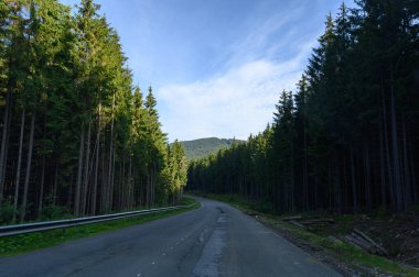 Dağ yolu. Taşlı manzara, bulutlu güneşli gökyüzü ve güzel asfalt yol. Seyahat geçmişi. Dağlarda otoyol