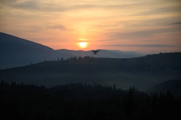 Silhouette Drone flying on mountain sunrise sky with cloud, Aerial photography. mountains landscape with sun and alpine pines. Sunrise