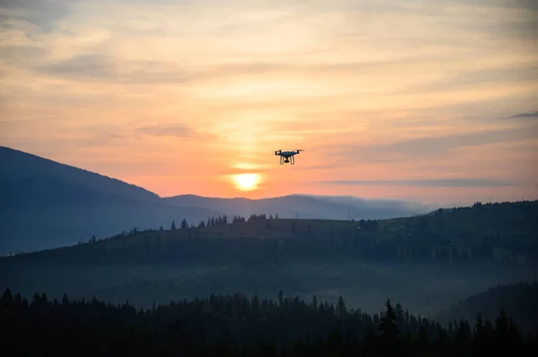 Silhouette Drone flying on mountain sunrise sky with cloud, Aerial photography. mountains landscape with sun and alpine pines. Sunrise