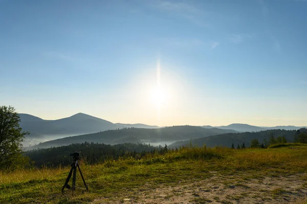 Amazing sunrise  sky with the camera on the tripod. Sky reflection. mountains summer sunrise landscape with sun and alpine pines. Landscape with rocks, sunny sky with clouds