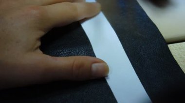 Bir kadın beyaz arka planda siyah bir kağıt kesiyor..