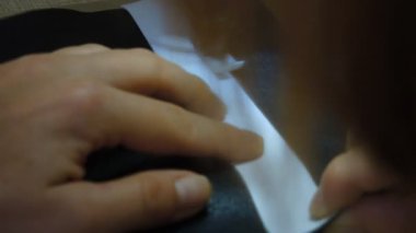 Bir kadın beyaz arka planda siyah bir kağıt kesiyor..