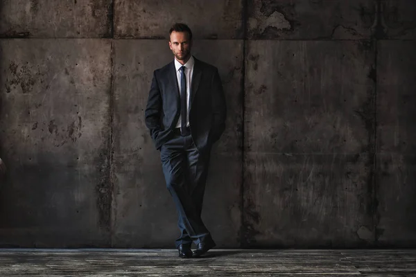 Schöner Mann im schwarzen Anzug auf Grunge-Hintergrund. — Stockfoto