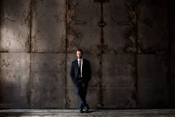 Guapo hombre vistiendo traje negro sobre un fondo grunge . —  Fotos de Stock