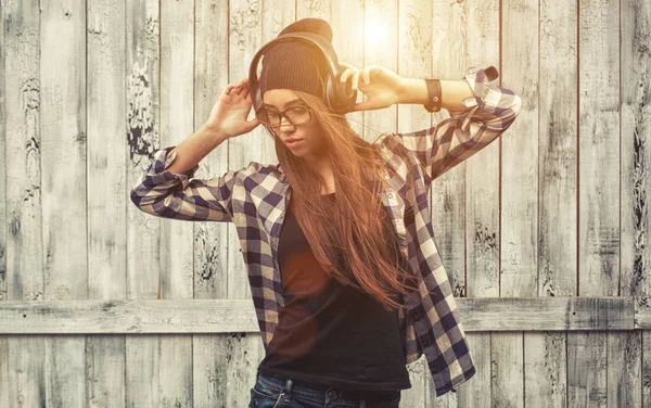 Hipster girl in glasses, headphones and black beanie — Stock Photo, Image