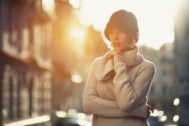 Açık havada örgü süveter ve klasik şapka giyen genç bir kızın moda kadın portresi. Avrupa 'da güzel bir gün batımı ışığı.