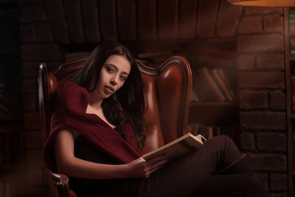 Woman resting with a book near fireplace — Stock Photo, Image