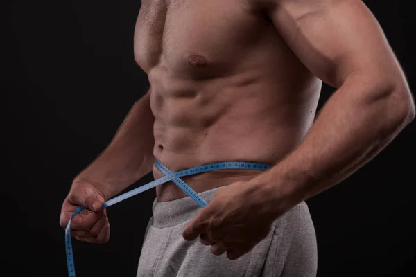 Fisiculturista com uma fita métrica em torno de seu estômago — Fotografia de Stock