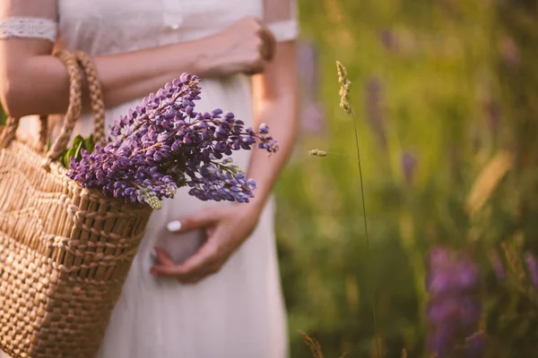 Manos de mujer sosteniendo una cesta con flores silvestres — Foto de Stock