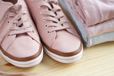 Kadın s snickers ve giysi yığını. Kot pantolon, gömlek, snickers ahşap masa ve beyaz arka plan yalıtım