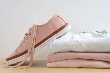 Kadın s snickers ve giysi yığını. Kot pantolon, gömlek, snickers ahşap masa ve beyaz arka plan yalıtım