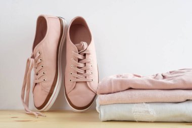 Kadın s snickers ve giysi yığını. Kot pantolon, gömlek, snickers ahşap masa ve beyaz arka plan yalıtım