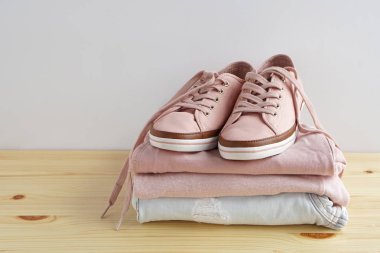 Kadın s snickers ve giysi yığını. Kot pantolon, gömlek, snickers ahşap masa ve beyaz arka plan yalıtım