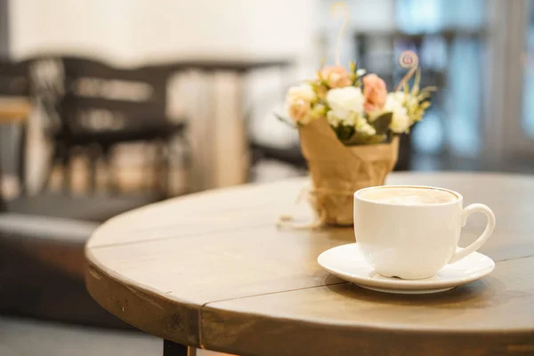 Xícara de cappuccino na mesa de madeira. Desfocado fundo café atrás . — Fotografia de Stock